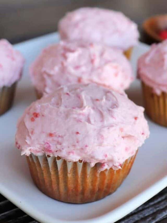 Raspberry cupcake with pink frosting sit on a white plate.