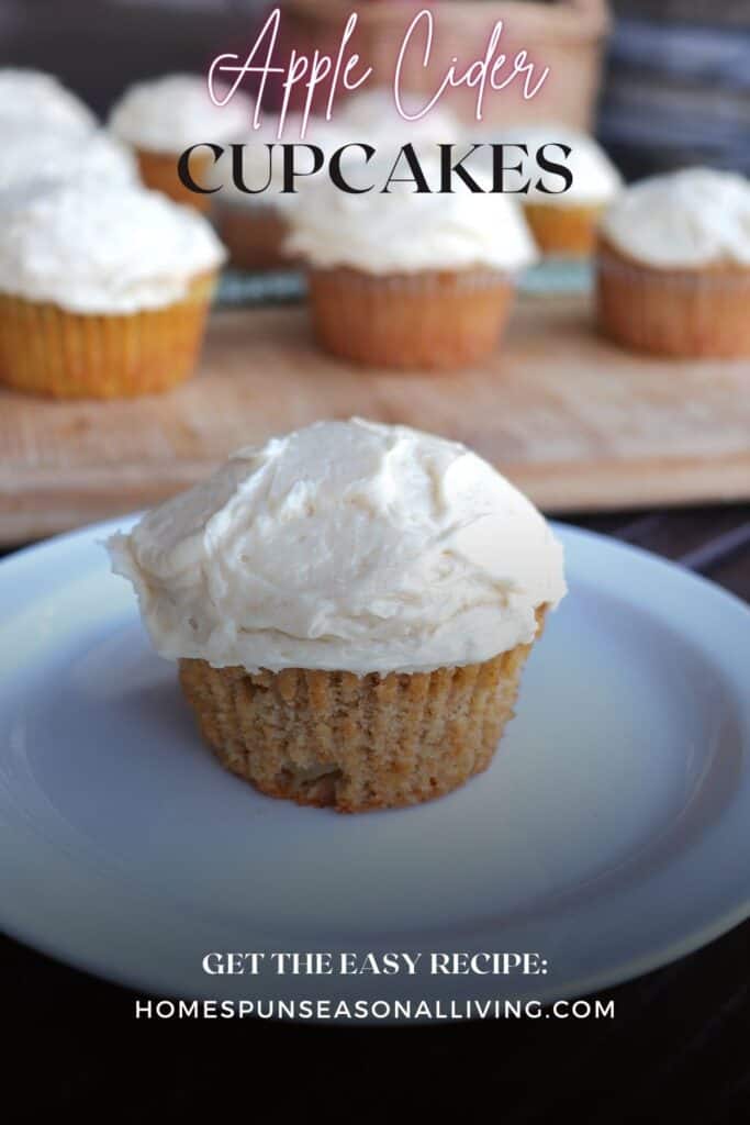 A frosted cupcake sits on a white plate with more cupcakes in the background. Text overlay reads: Apple Cider Cupcakes.