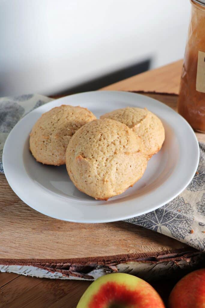 Close up of cookies on a plate with fresh apples in the foreground.