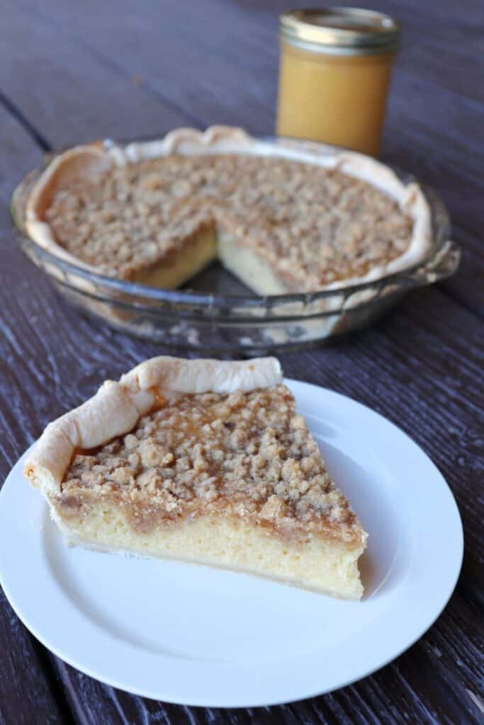 A slice of crumble topped applesauce pie with remaining pie in the background.