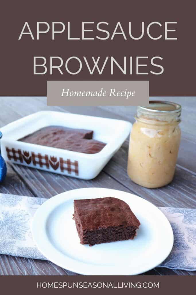 A brownie sits on a plate with a pan of brownies and a jar of applesauce in the background. Text overlay reads: Applesauce Brownies: Homemade Recipe.