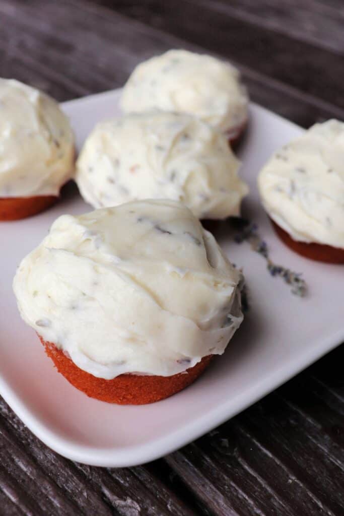 A platter of frosted cupcakes, with a close-up of one showing the lavender flowers in the frosting.