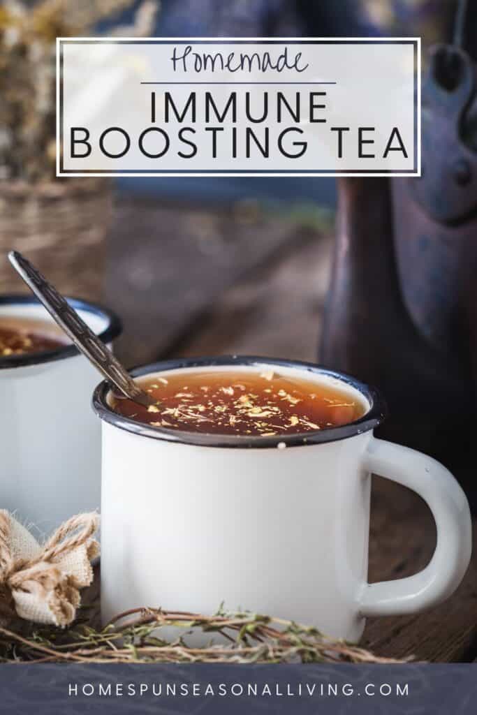 A white enamel cup full of tea with herbs floating on top, a spoon sticks out of the cup. A teapot in the background. Text overlay reads Homemade Immune Boosting Tea.