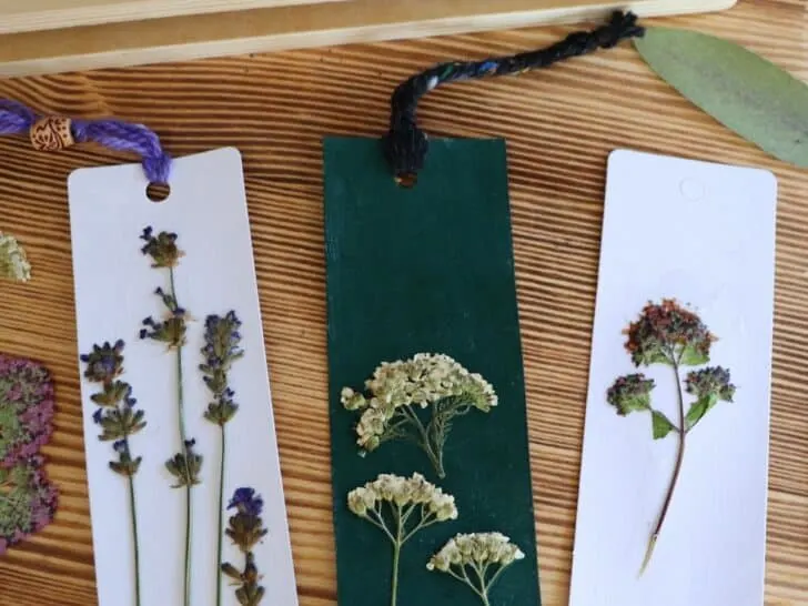 3 bookmarks decorated with pressed flowers sit on a table.