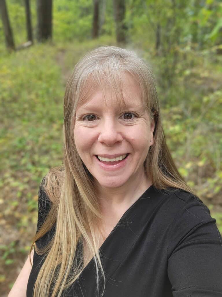 A picture of Kathie Lapcevic standing in the forest. 